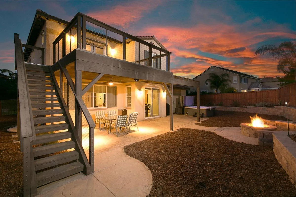 Elevated composite deck with metal frame patio cover, integrated lighting, and fire pit at dusk