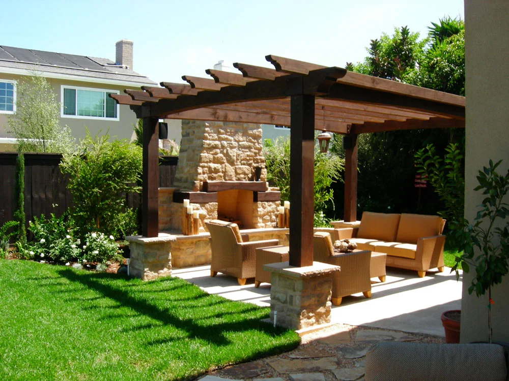 Wood pergola with stone fireplace, concrete patio, and wicker seating furniture