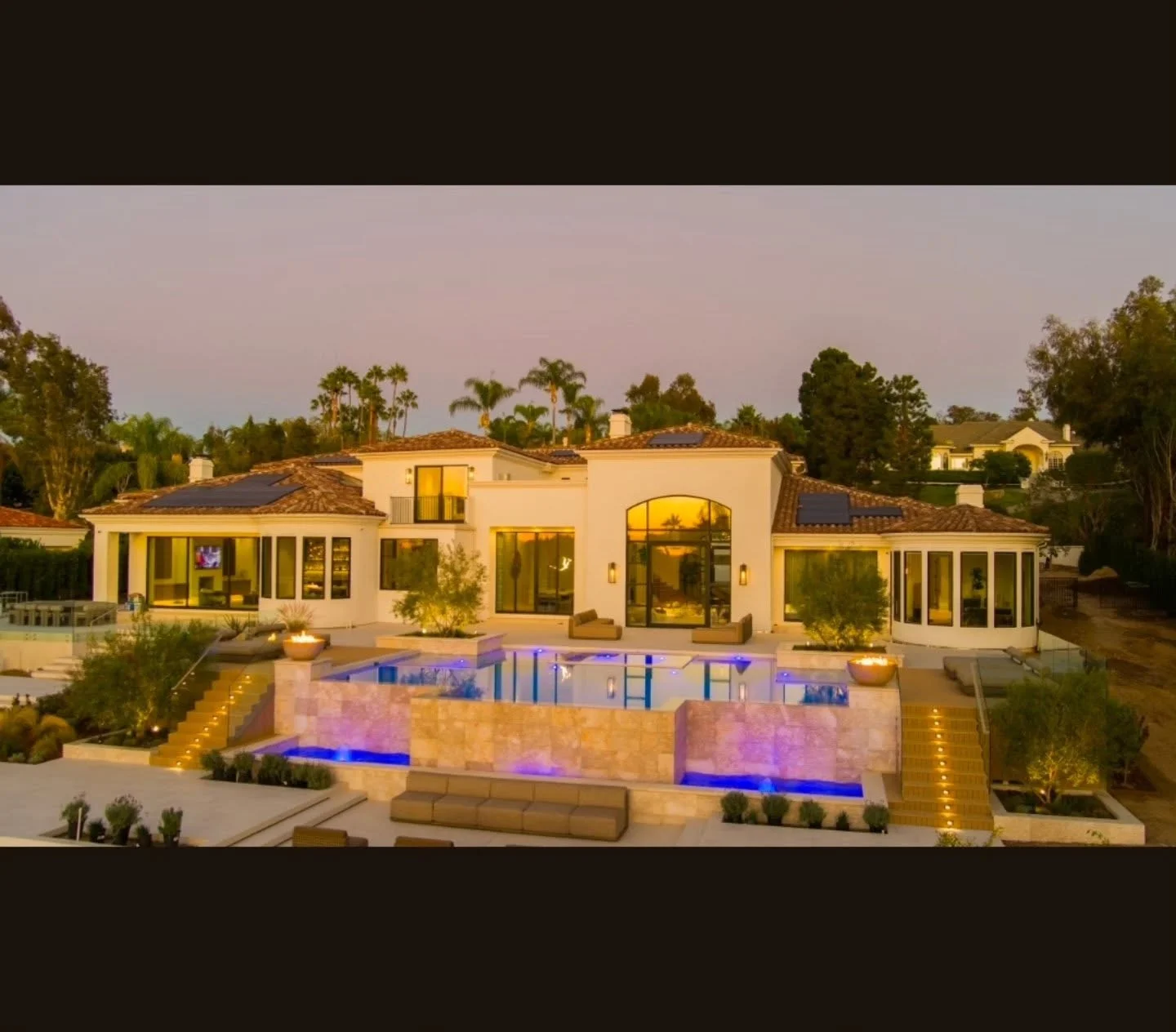 Travertine pool deck with blue LED lighting, raised spa walls, and integrated landscape lighting