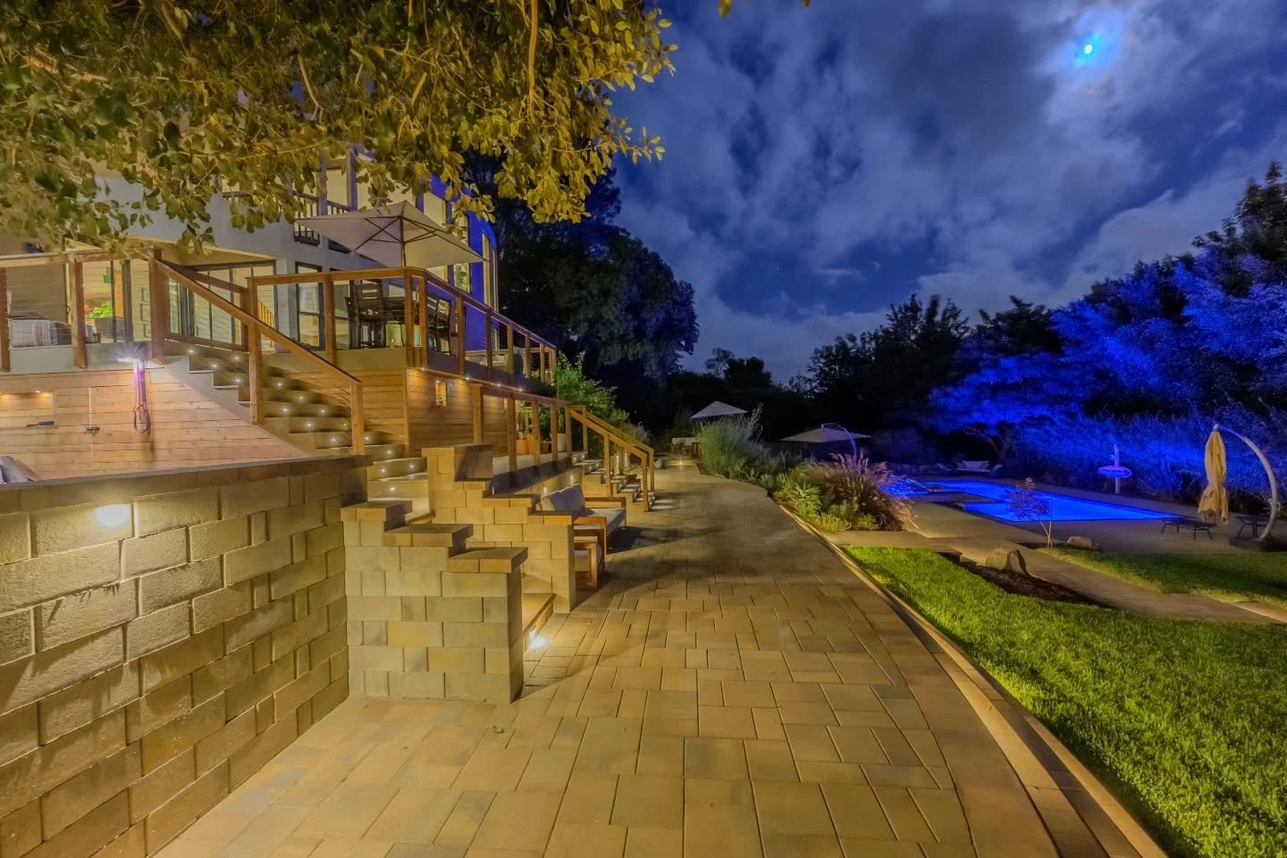 Composite deck with LED lighting, wooden railings, and built-in seating at dusk