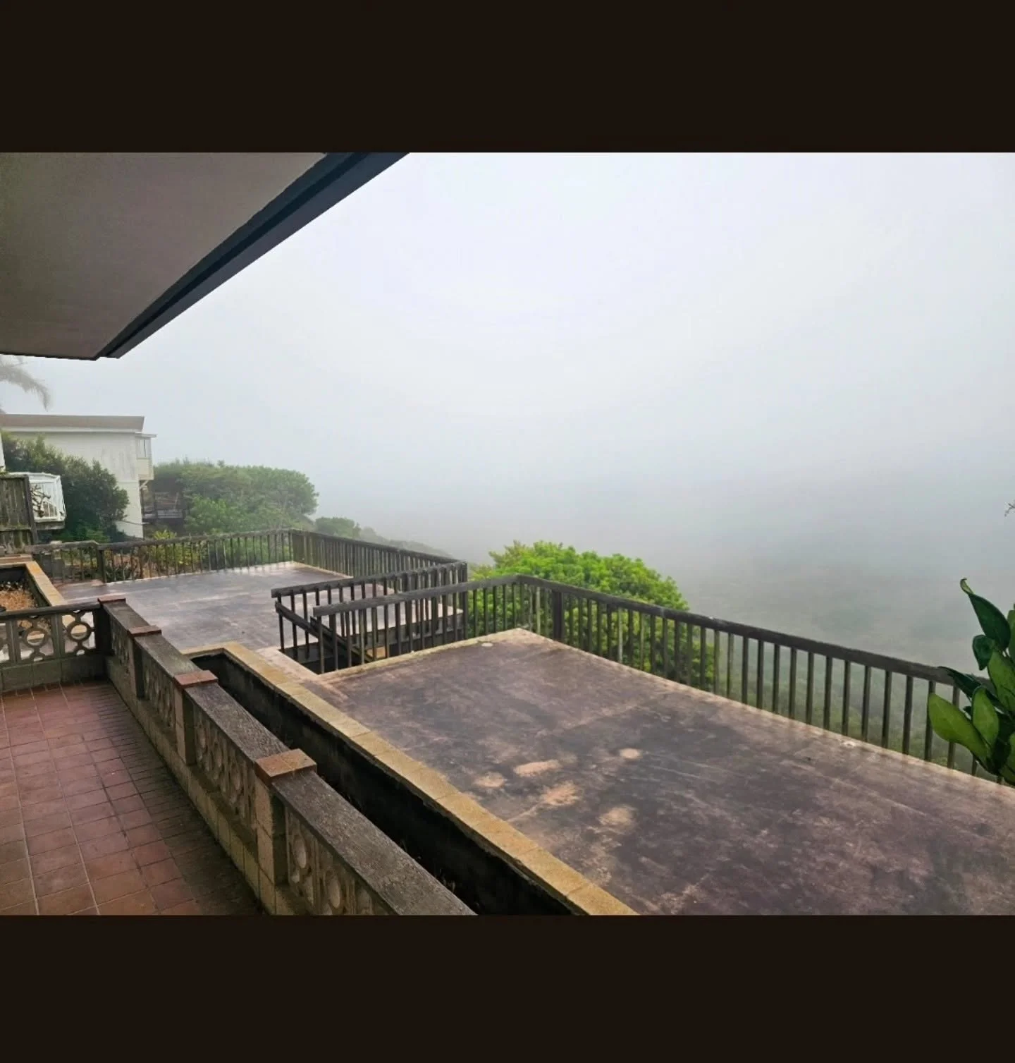 Composite deck with black metal railings, patio cover, and built-in seating walls on hillside
