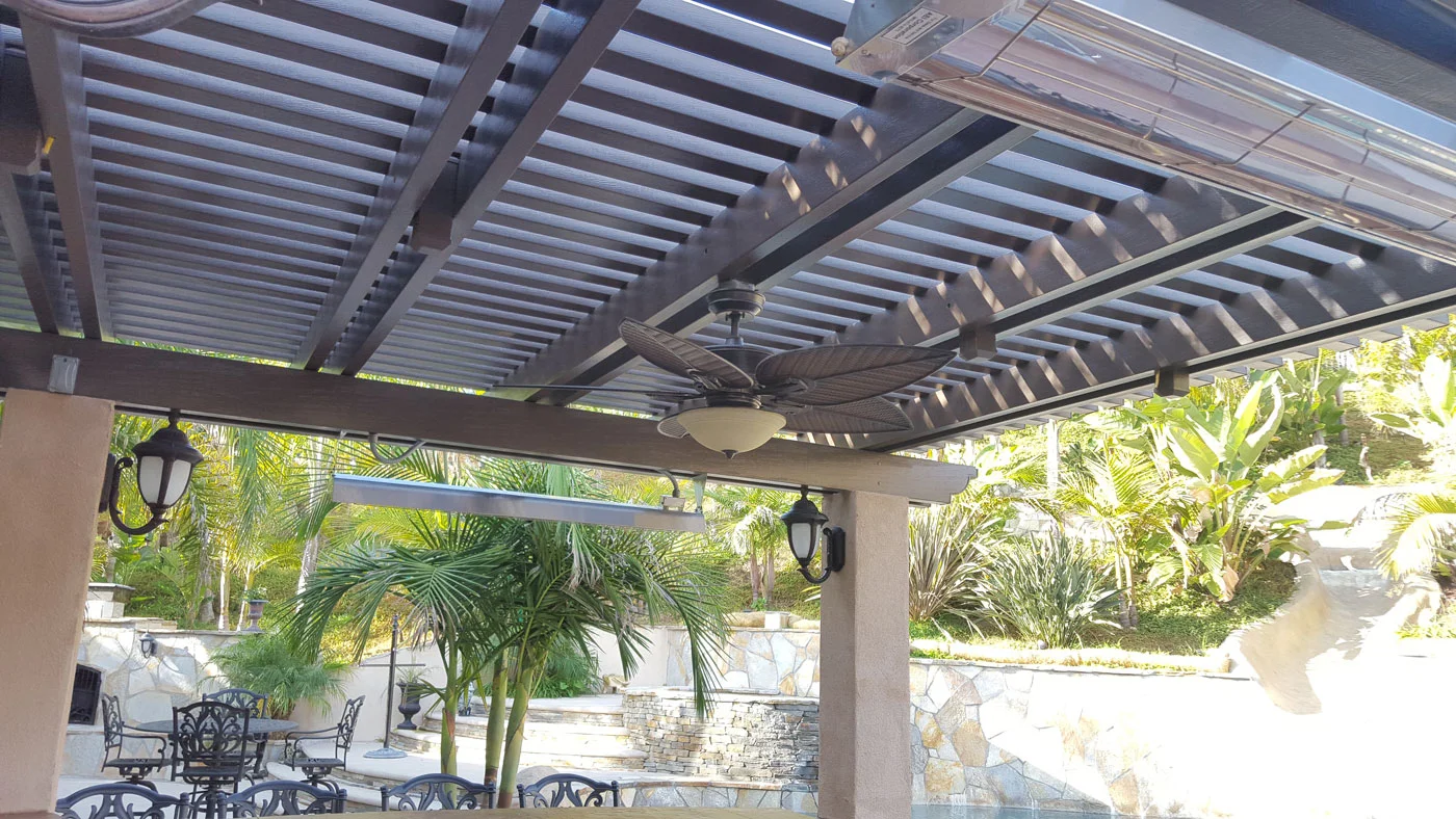 Alumawood patio cover with louver slats, ceiling fan, and recessed lighting over stone columns