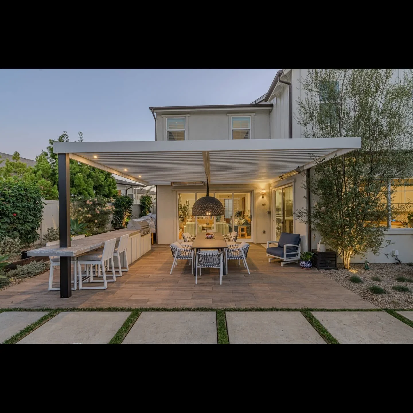 Modern aluminum pergola with LED lights, composite deck, built-in bar, and dining area